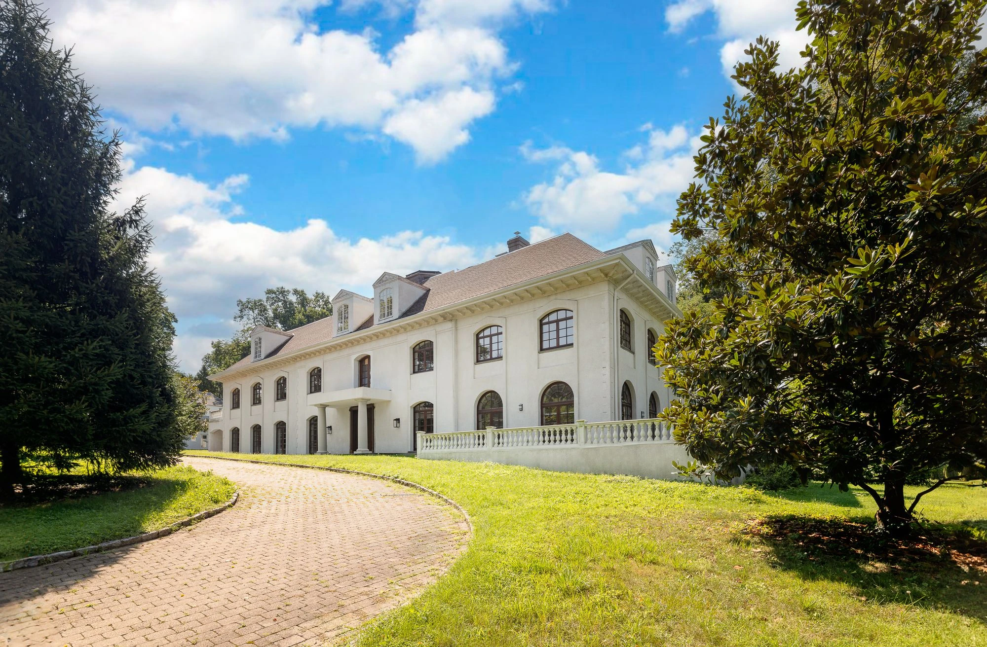 Long white mansion with arched windows and a curved driveway at 5040 Independence Avenue in Riverdale