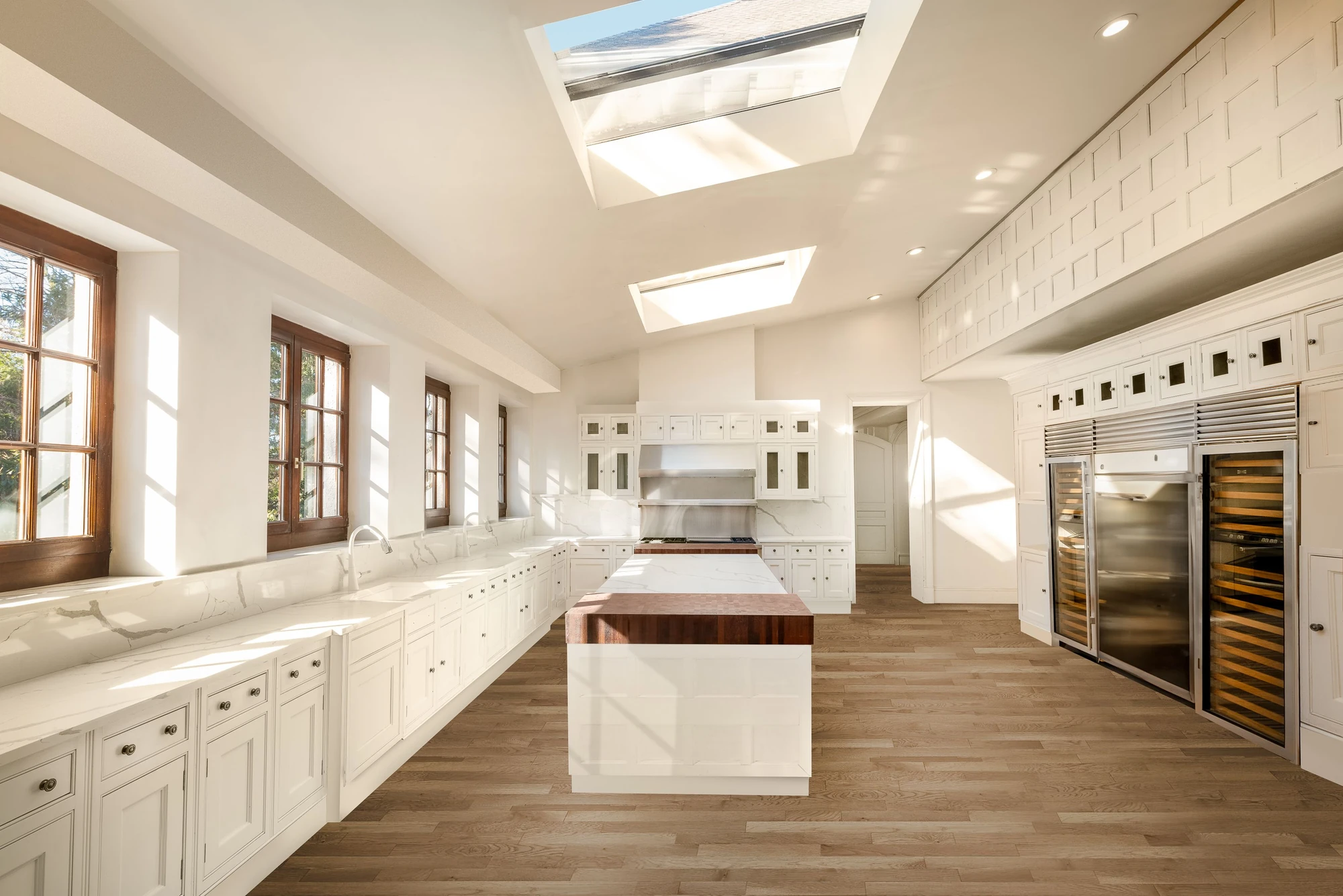 Large white kitchen with two skylights, a central island, and wood-framed windows at 5040 Independence Avenue