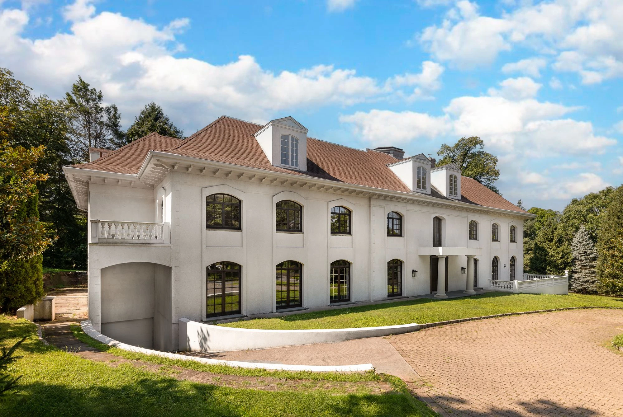 Long side elevation of the white mansion with two levels of arched windows and tall roof dormers at 5040 Independence Avenue