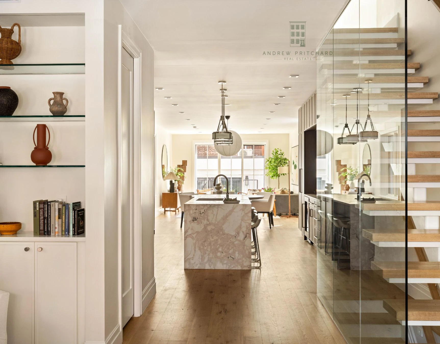 Long open kitchen with marble island and glass staircase at 232 Eighth Street
