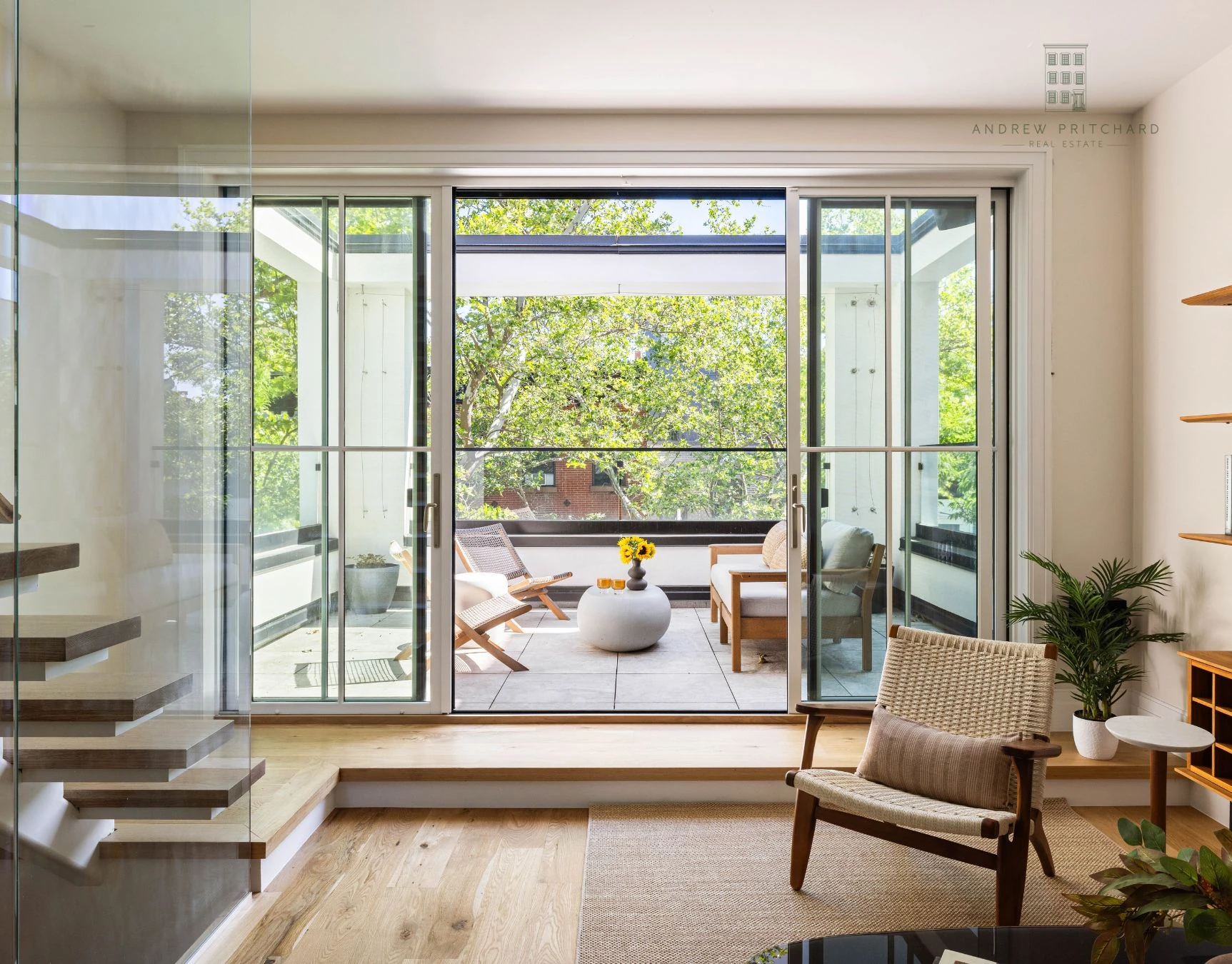 Bright living room with glass staircase and sliding doors opening to a terrace at 232 Eighth Street