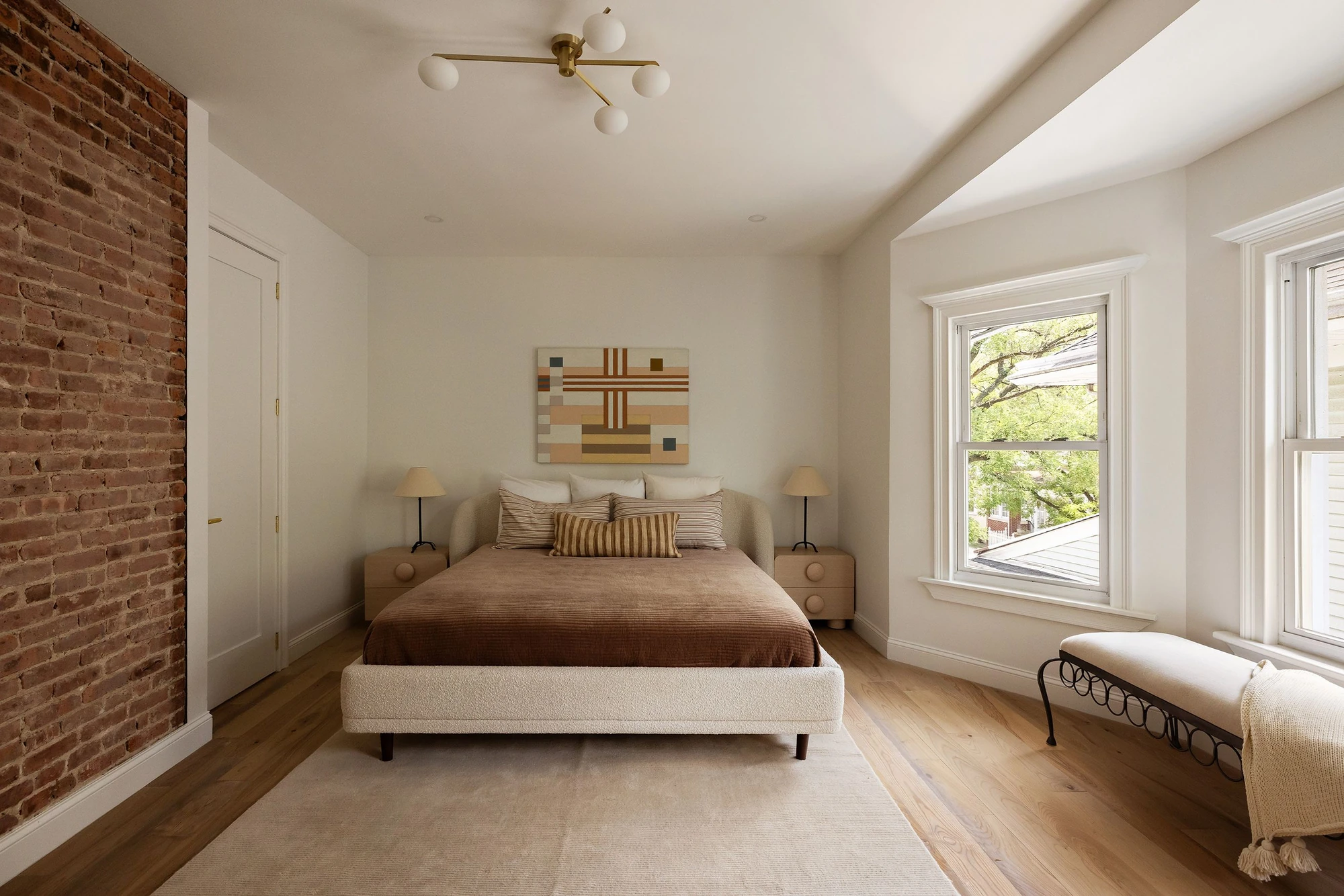 Bedroom with an exposed-brick wall, angled window bay, and warm wood floor at 534 East 24th Street