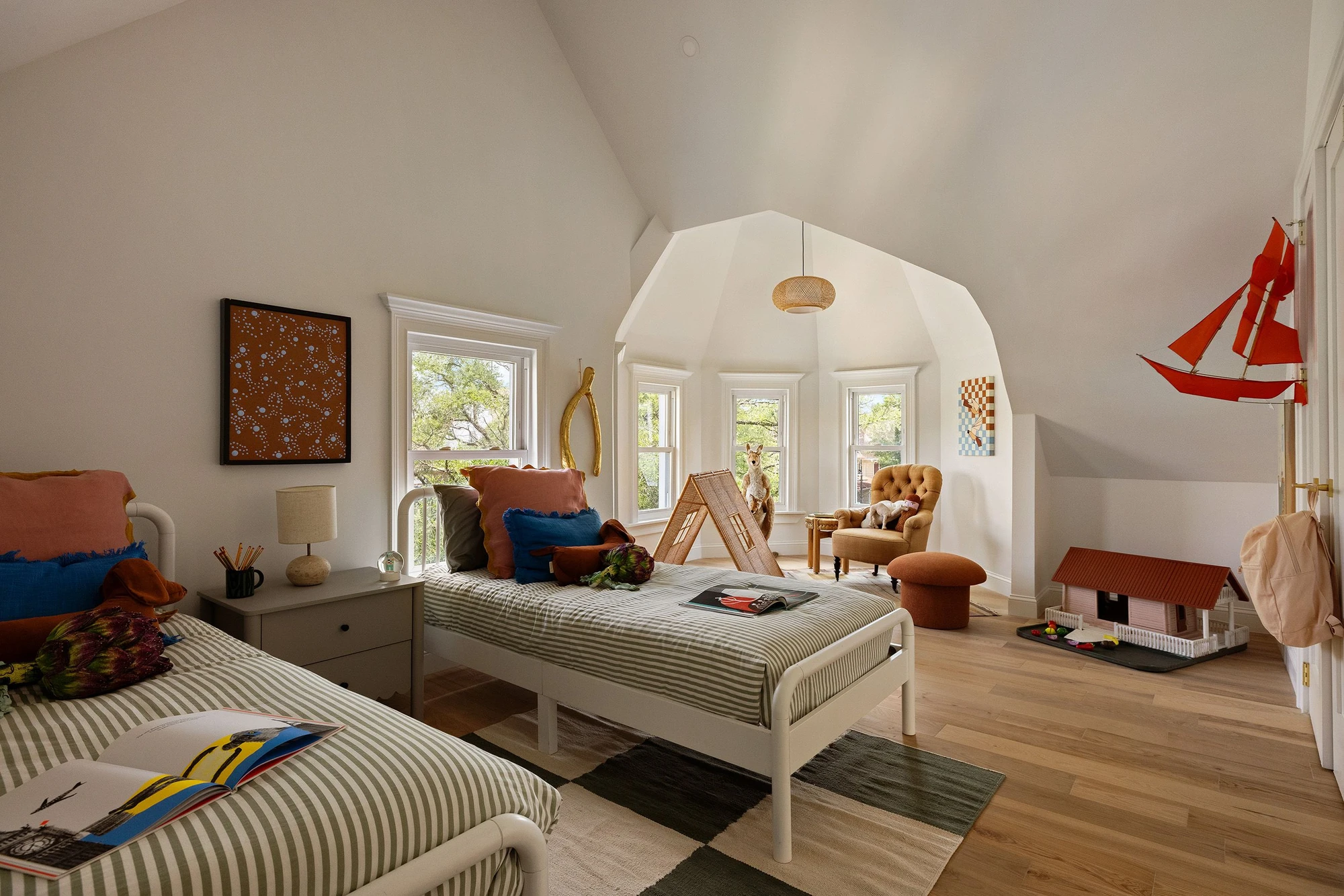 Bedroom with two beds, a hanging model sailboat, and a broad vaulted window bay at 534 East 24th Street