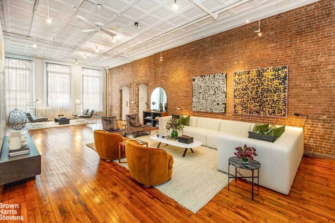Broad loft living room with a long brick wall and patterned white ceiling at 39 Worth Street