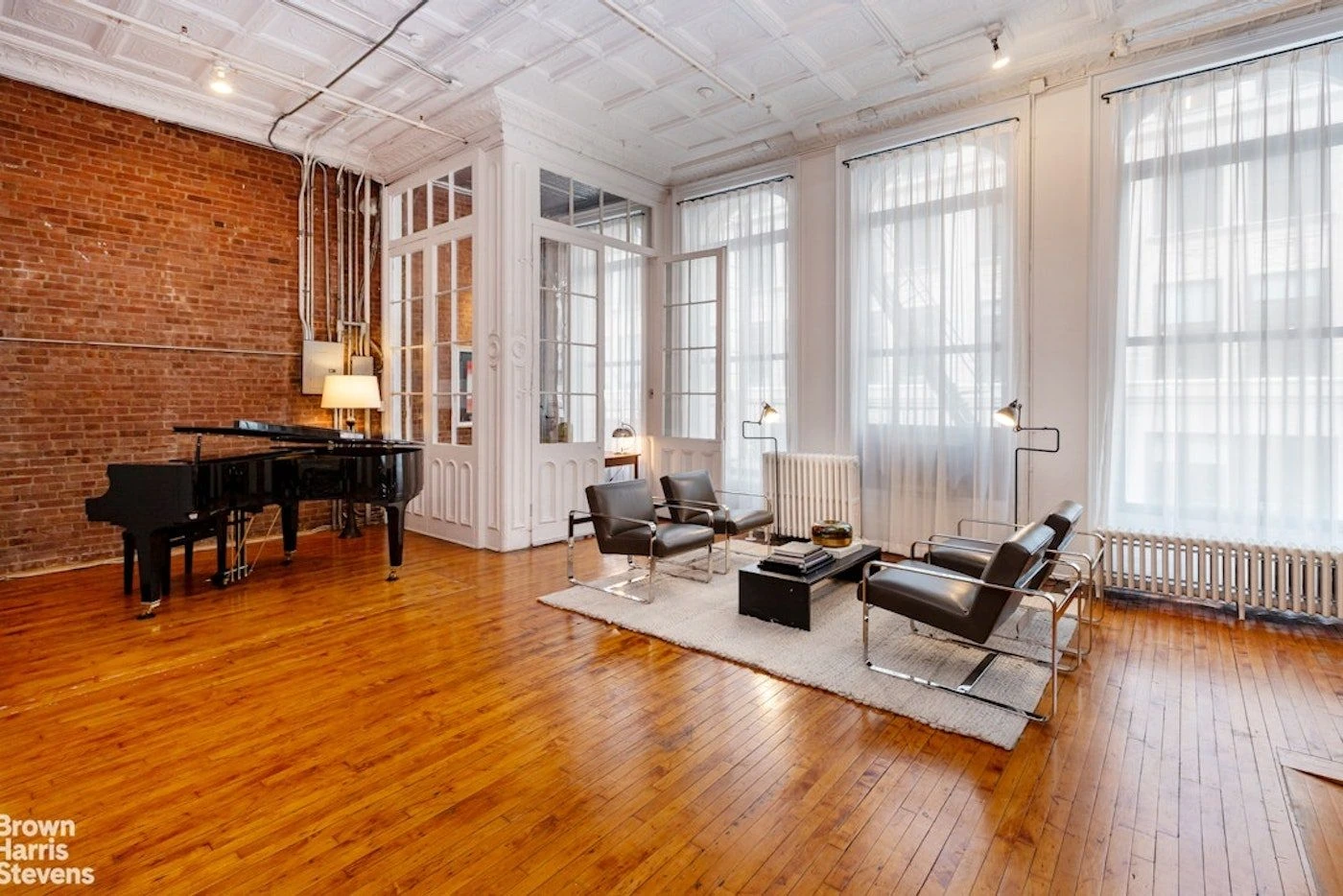 Tall loft windows, a black piano, and exposed brick at 39 Worth Street