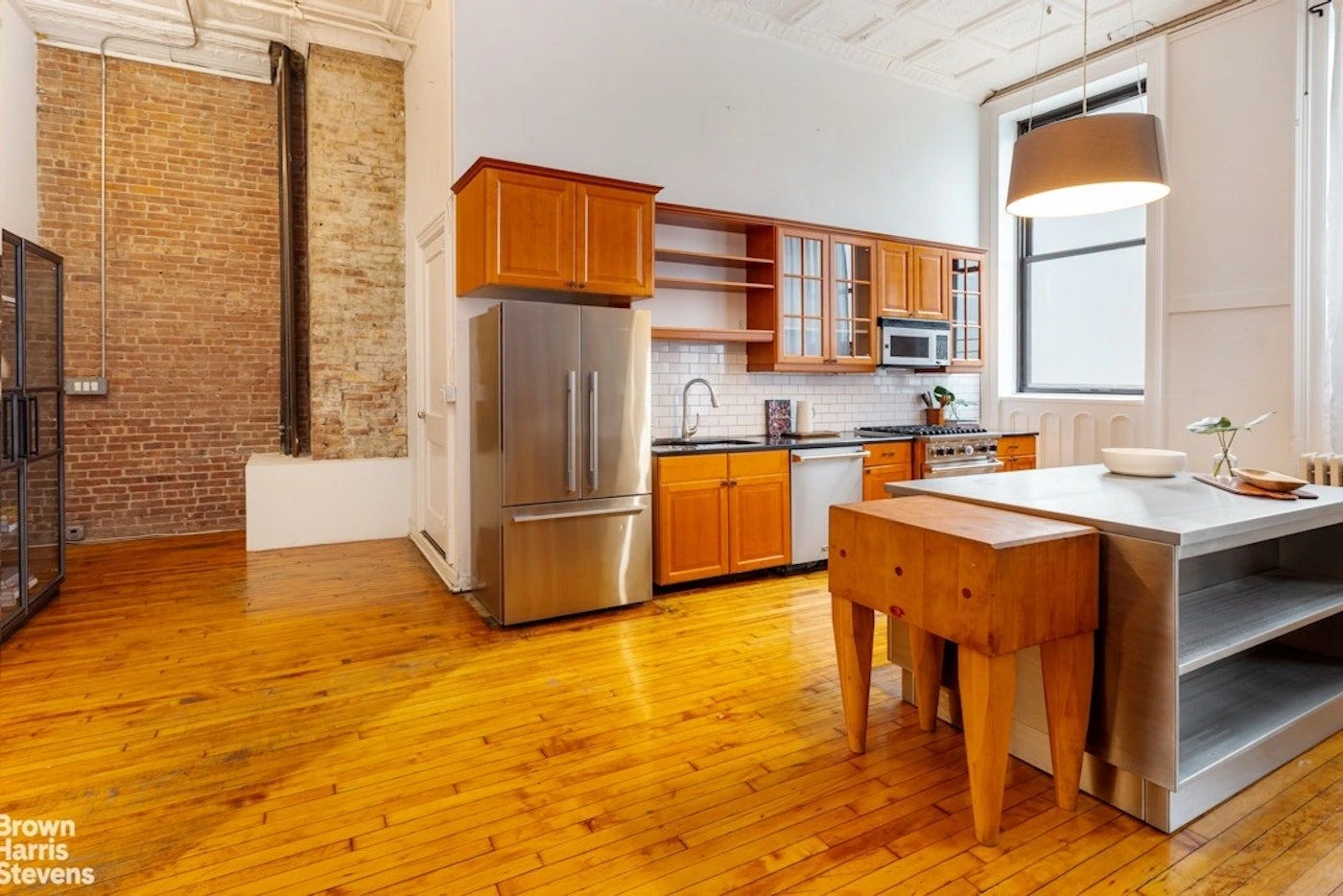 Wood kitchen cabinets and an island beside exposed brick at 39 Worth Street