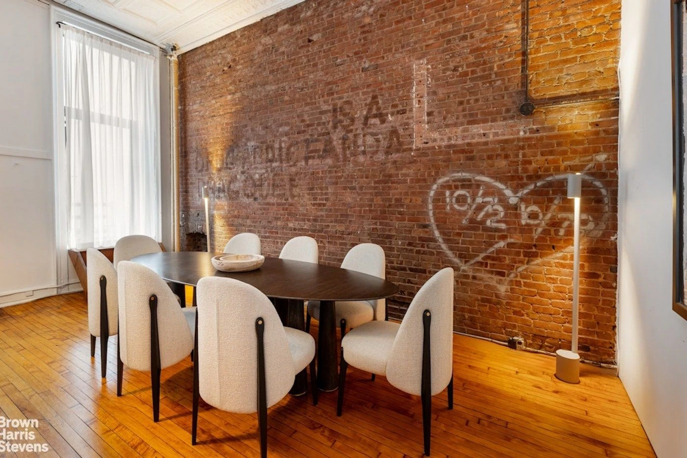 Dining room at 39 Worth Street with faded lettering and graffiti-like markings on an exposed-brick wall