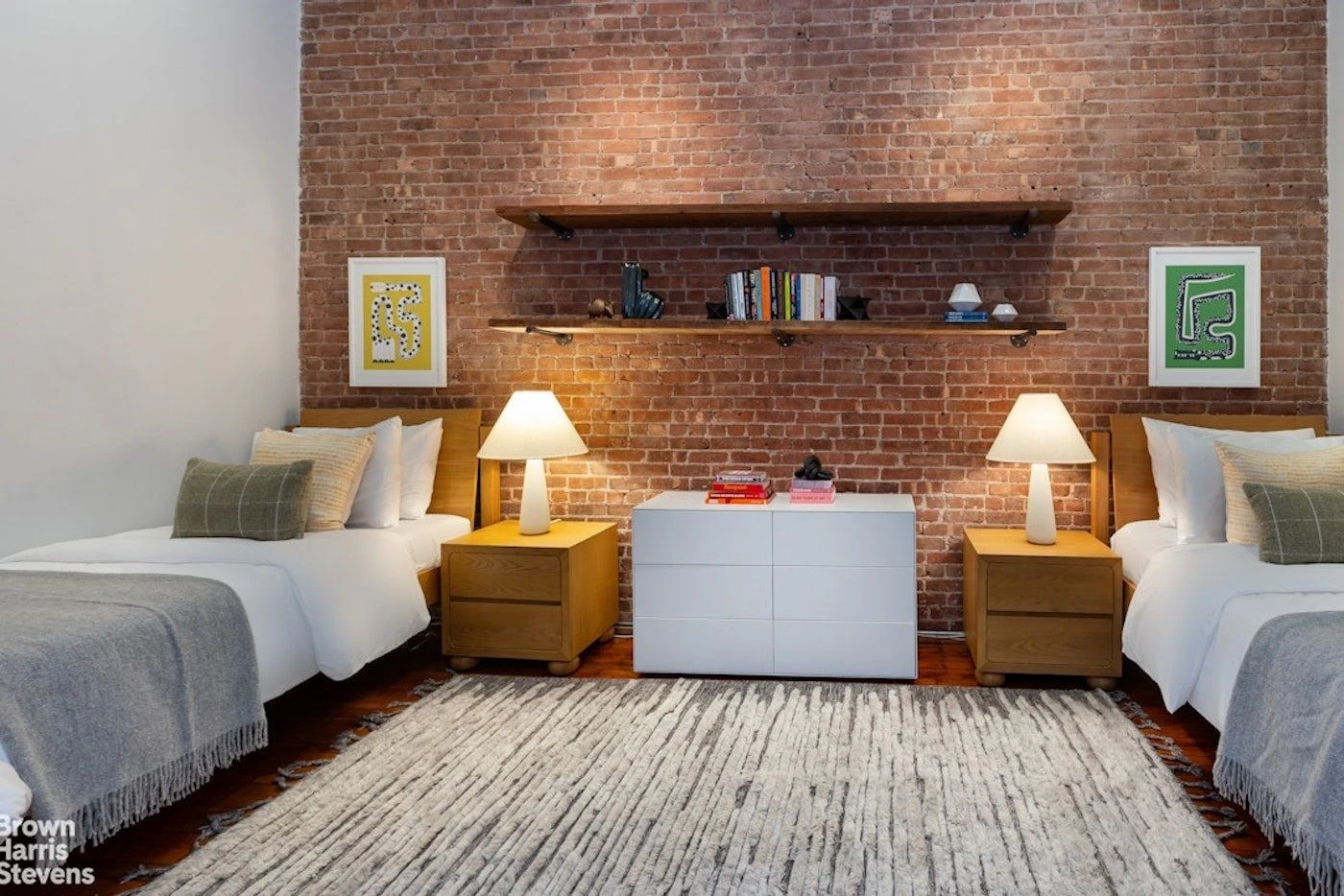 Twin beds beneath shelves on an exposed-brick wall at 39 Worth Street