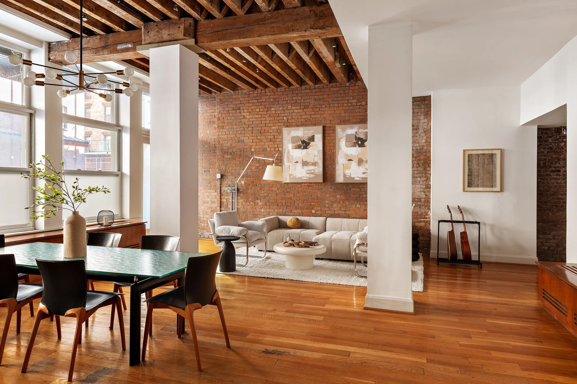 Open living and dining room with red-brick walls, timber beams, and white columns at 62 Beach Street