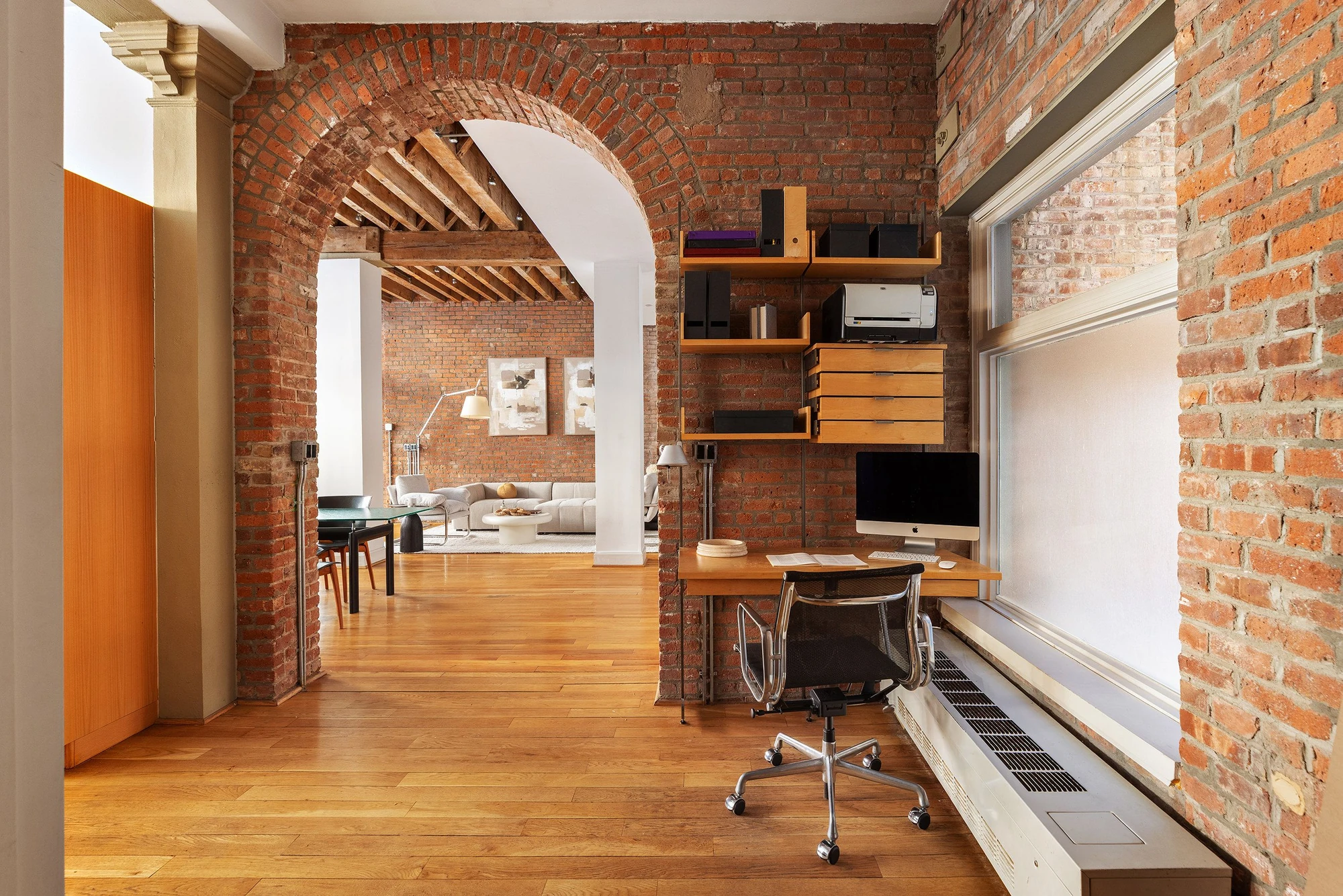 Red-brick arch framing the living room beneath exposed wood ceiling beams at 62 Beach Street