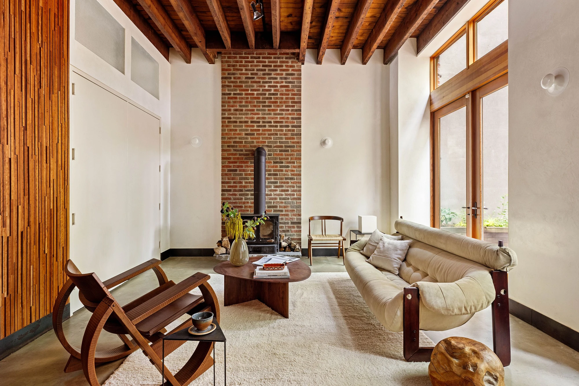 Living room with tall windows, timber ceiling beams, and a brick chimney at 497 Saint John's Place