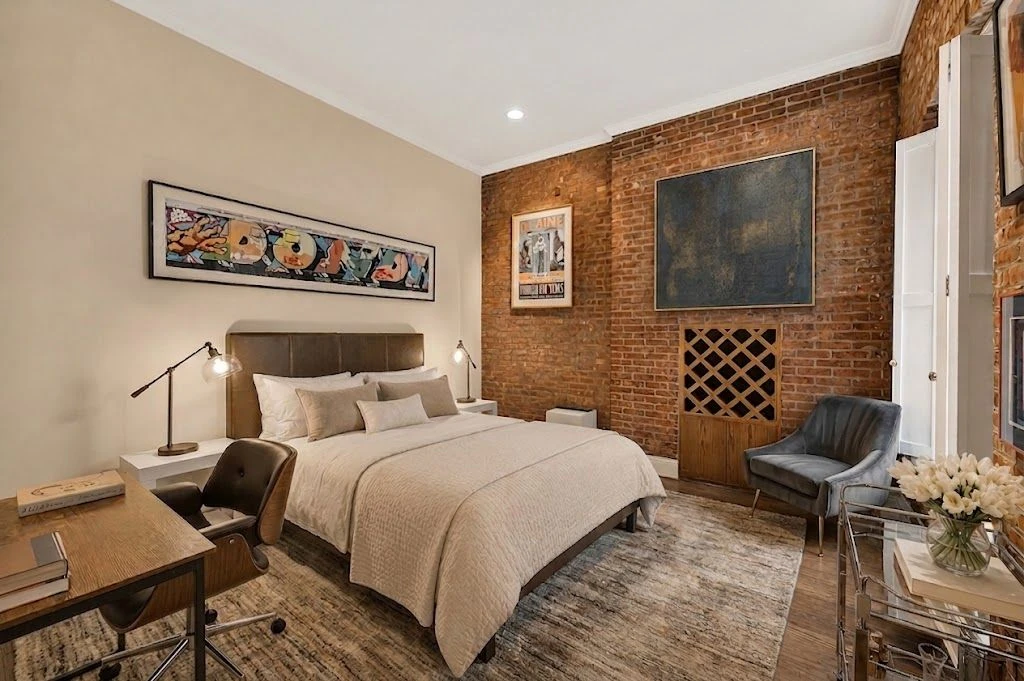 Listing imagery showing a bedroom with an exposed-brick wall at 203 East 13th Street