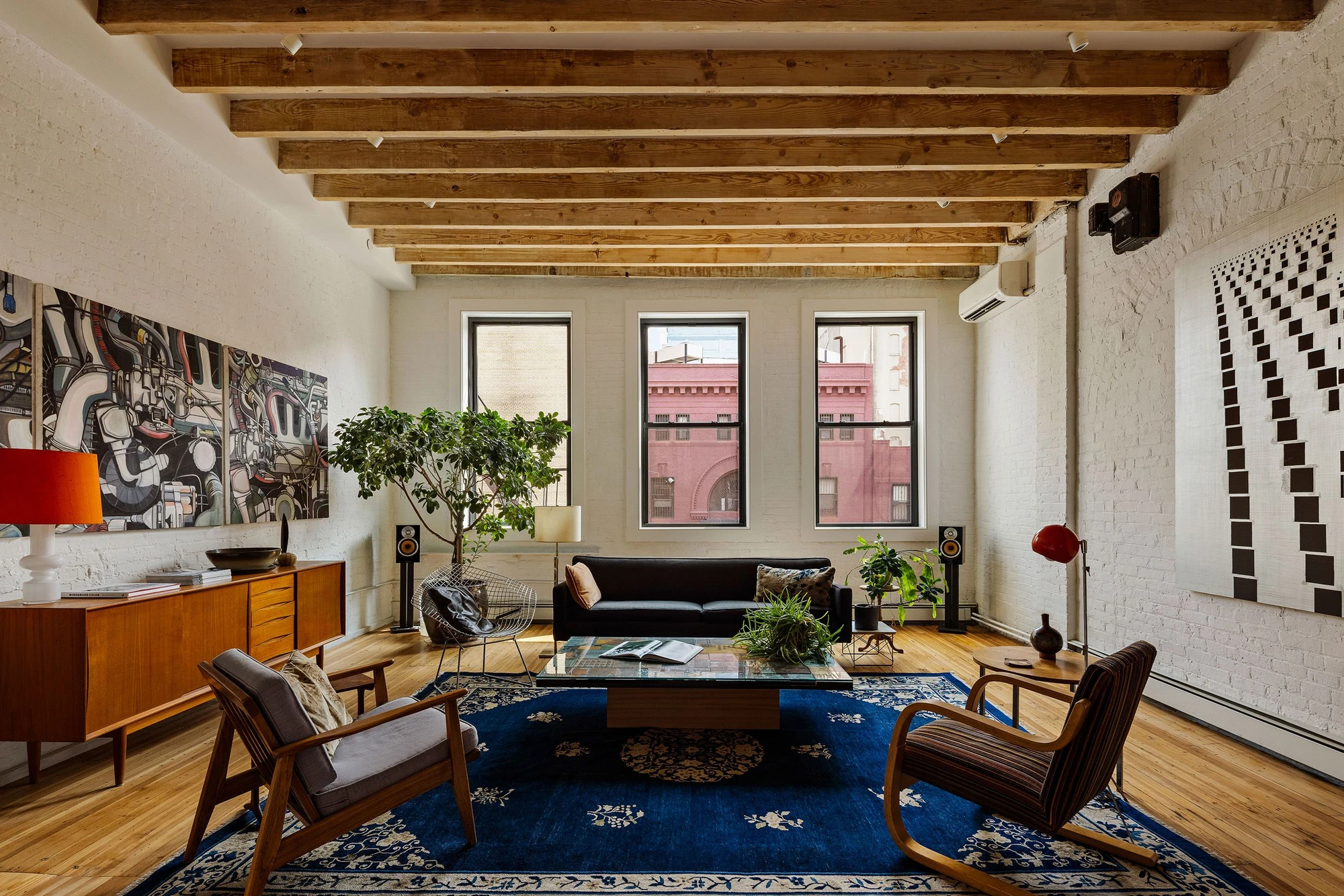 Living room with exposed ceiling beams, white-painted brick, and three front windows at 62 Washington Avenue