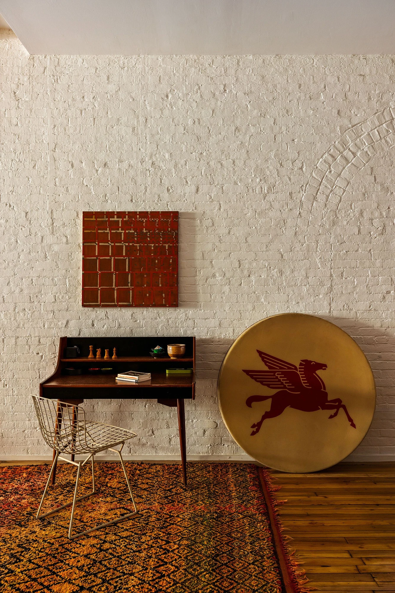 Chair and artwork against textured white-painted brick at 62 Washington Avenue