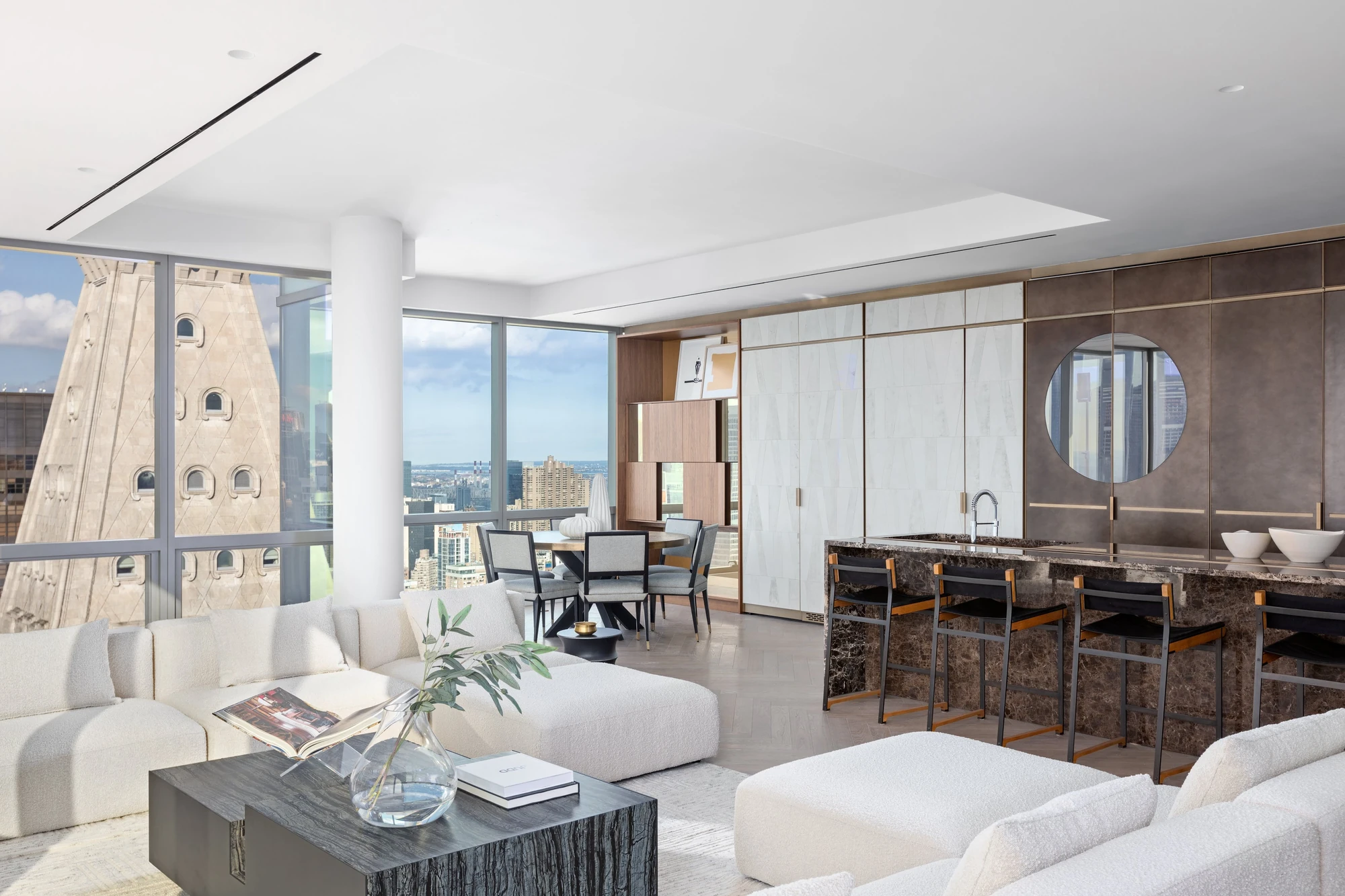 Dining table, dark stone island, and pale kitchen cabinetry with the MetLife Clock Tower visible through the adjacent windows
