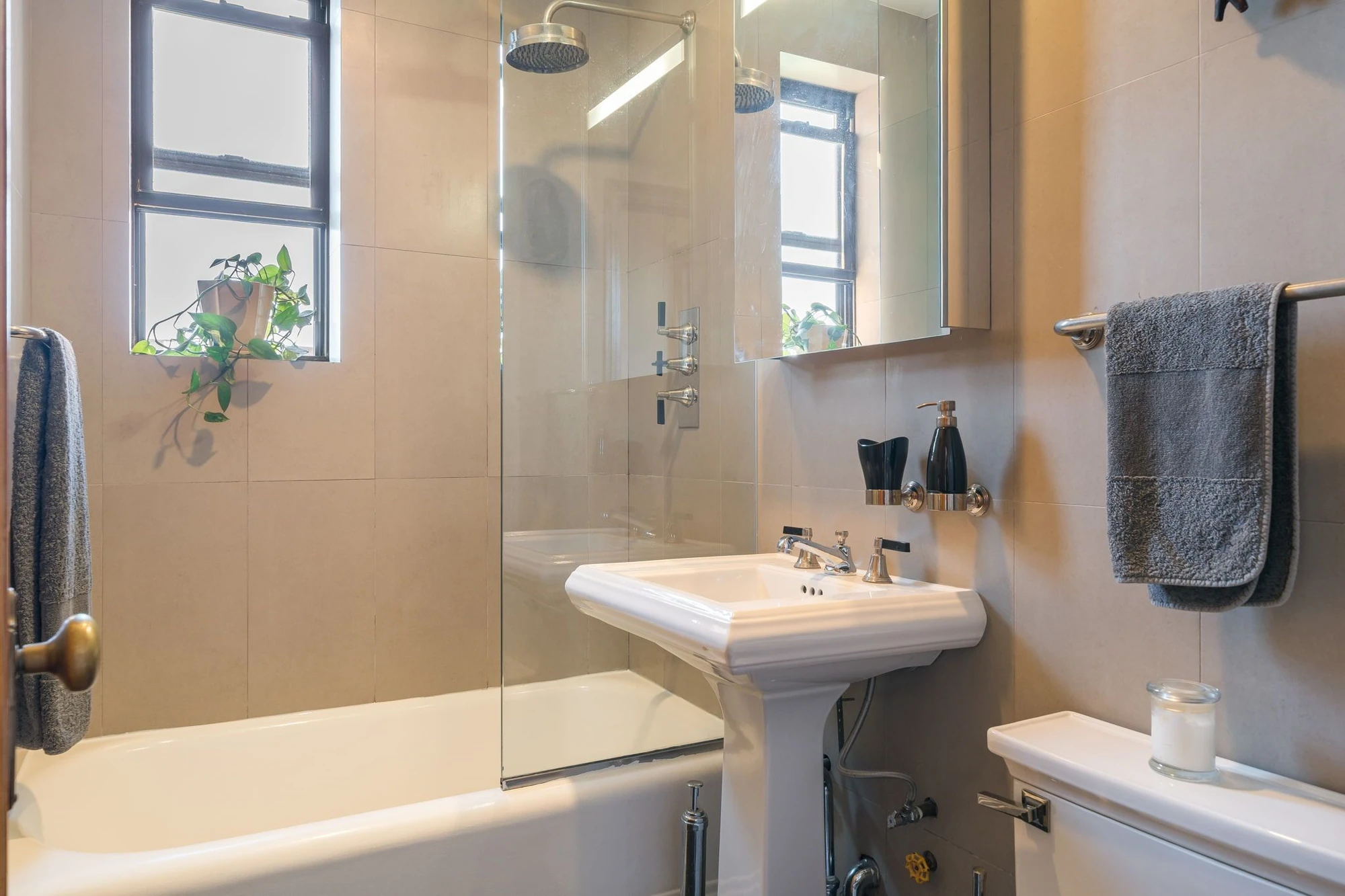 Windowed bathroom with a tub and pedestal sink at 1710 Avenue H #C5