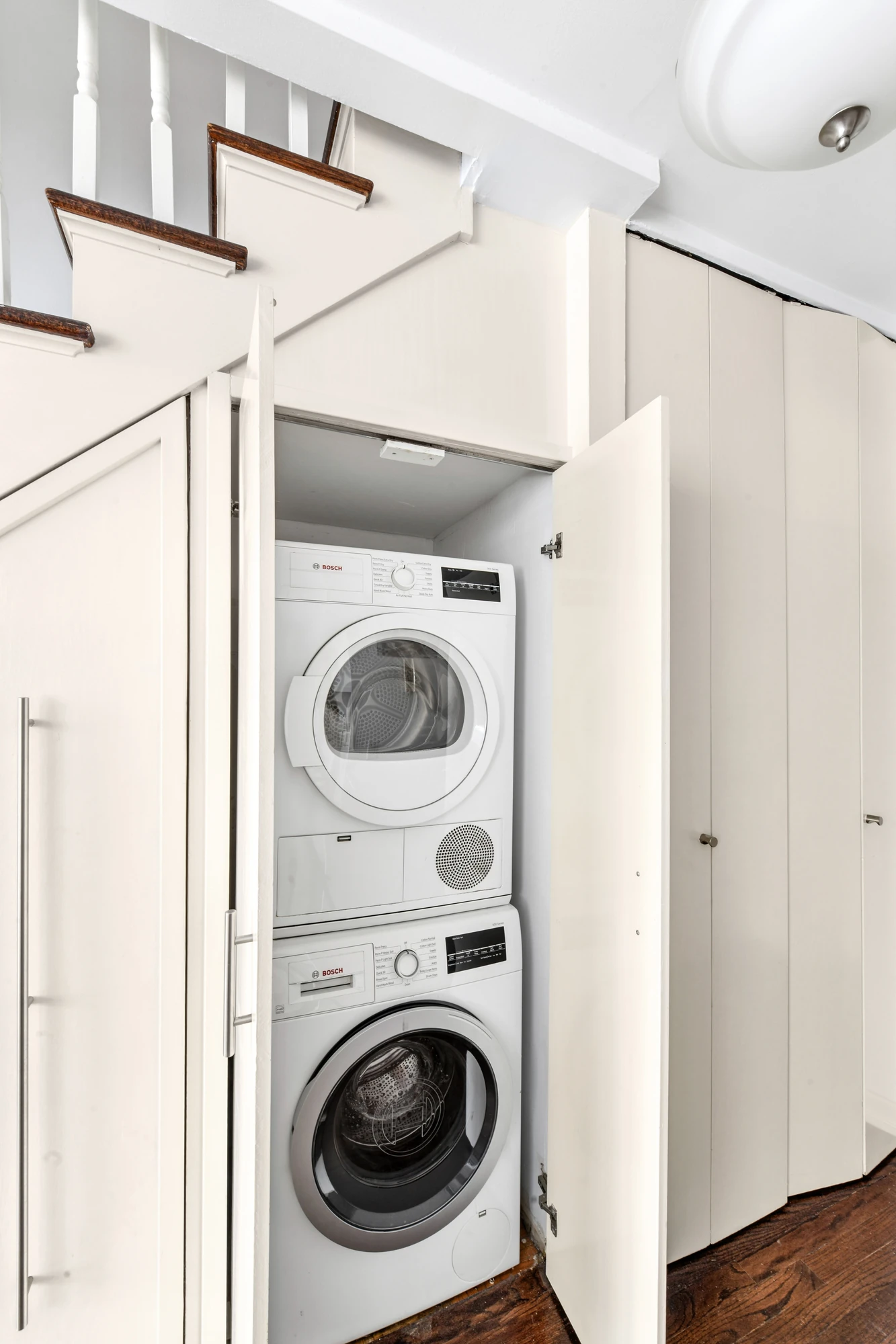 Stacked washer and dryer in a closet below the duplex staircase at 21 South End Avenue #207