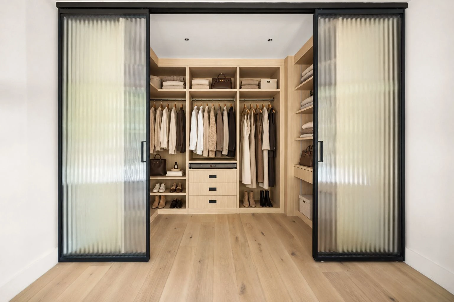 Built-in hanging rails, shelves and drawers behind frosted-glass sliding doors in the dressing room at 100 Scholes Street #2A