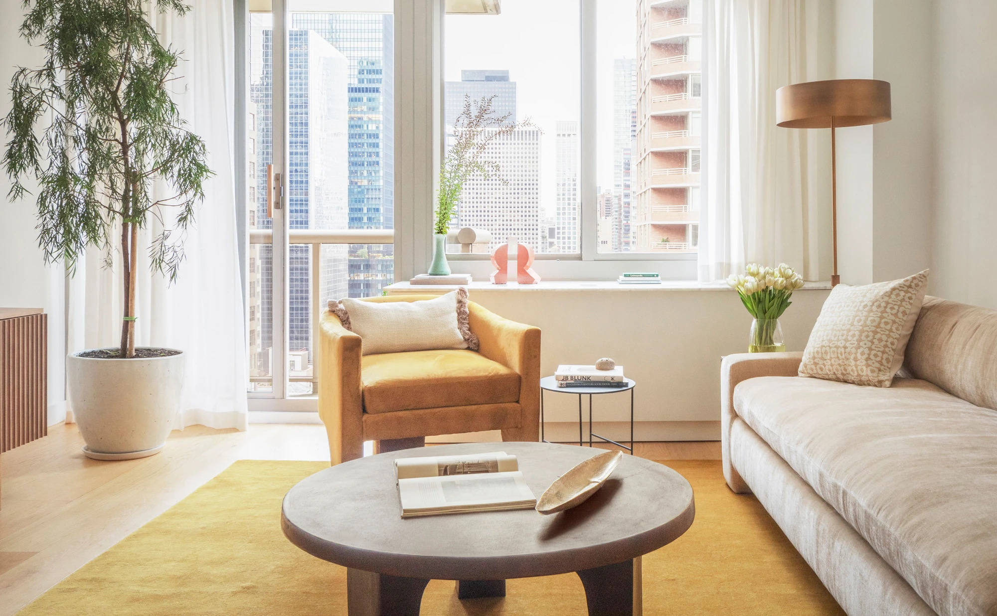 Living room with pale wood floors and a broad window wall at The Perrie, 234 East 46th Street #701