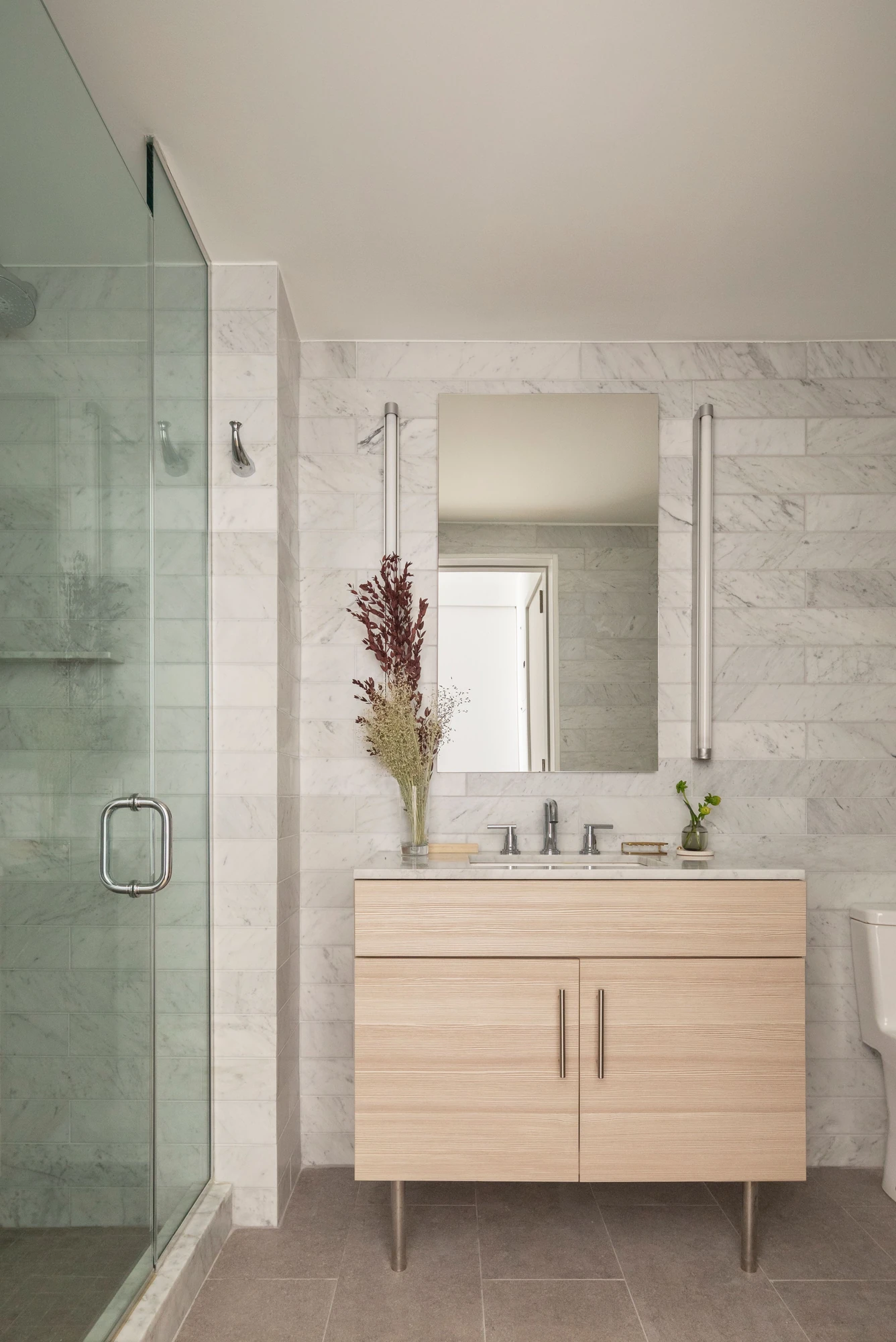 Bathroom with a wood vanity, stone surfaces and a glass-enclosed shower at The Perrie, 234 East 46th Street #701