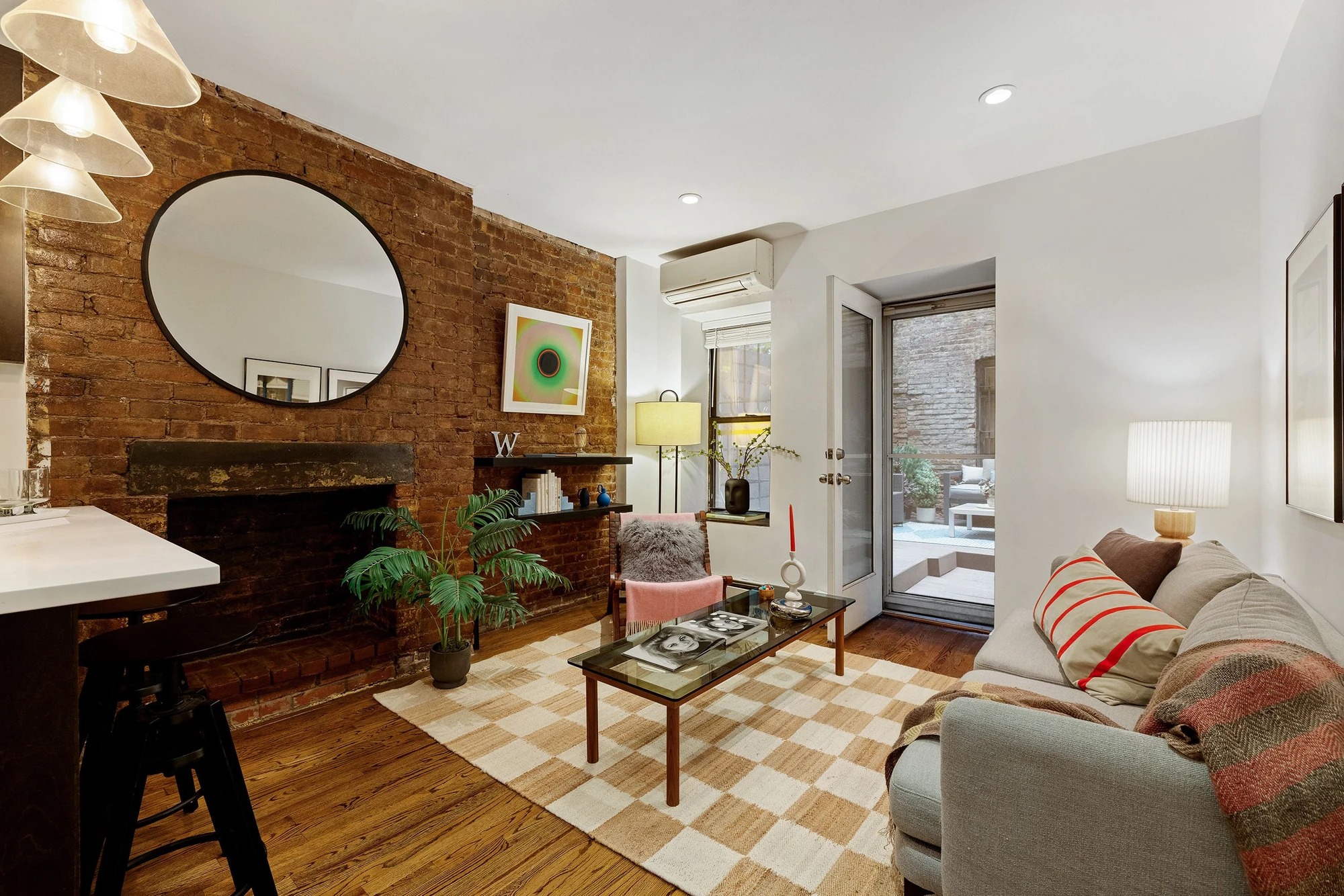Exposed brick and a decorative fireplace beside the living-room seating at 118 Suffolk Street #1B
