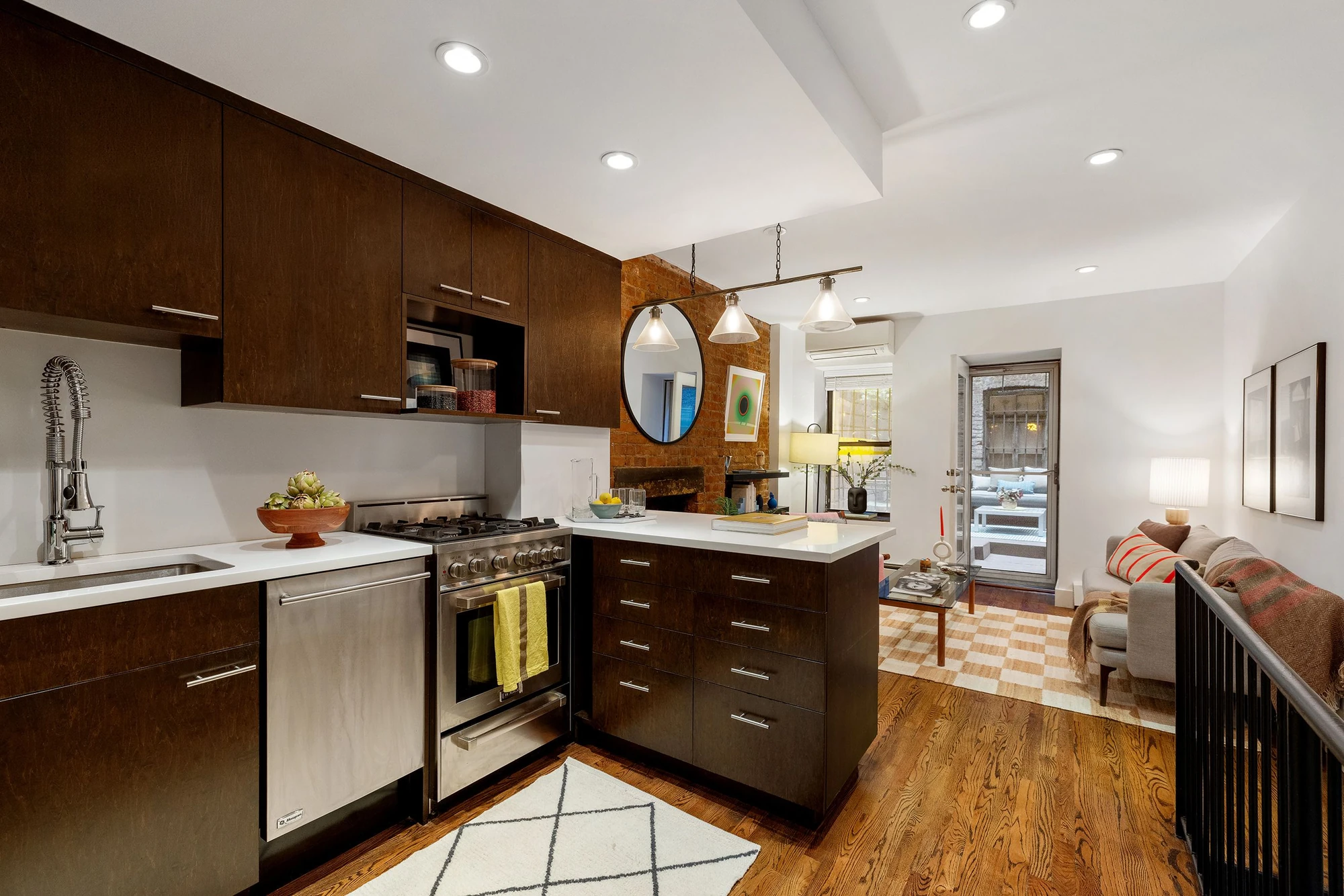 Dark wood kitchen cabinetry, stainless steel appliances and pale counters open to the living room at 118 Suffolk Street #1B