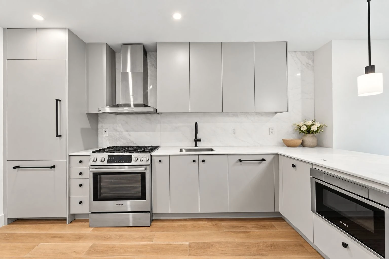 Developer illustration of a pale kitchen with a peninsula and stainless steel appliances at 696 Chauncey Street #1