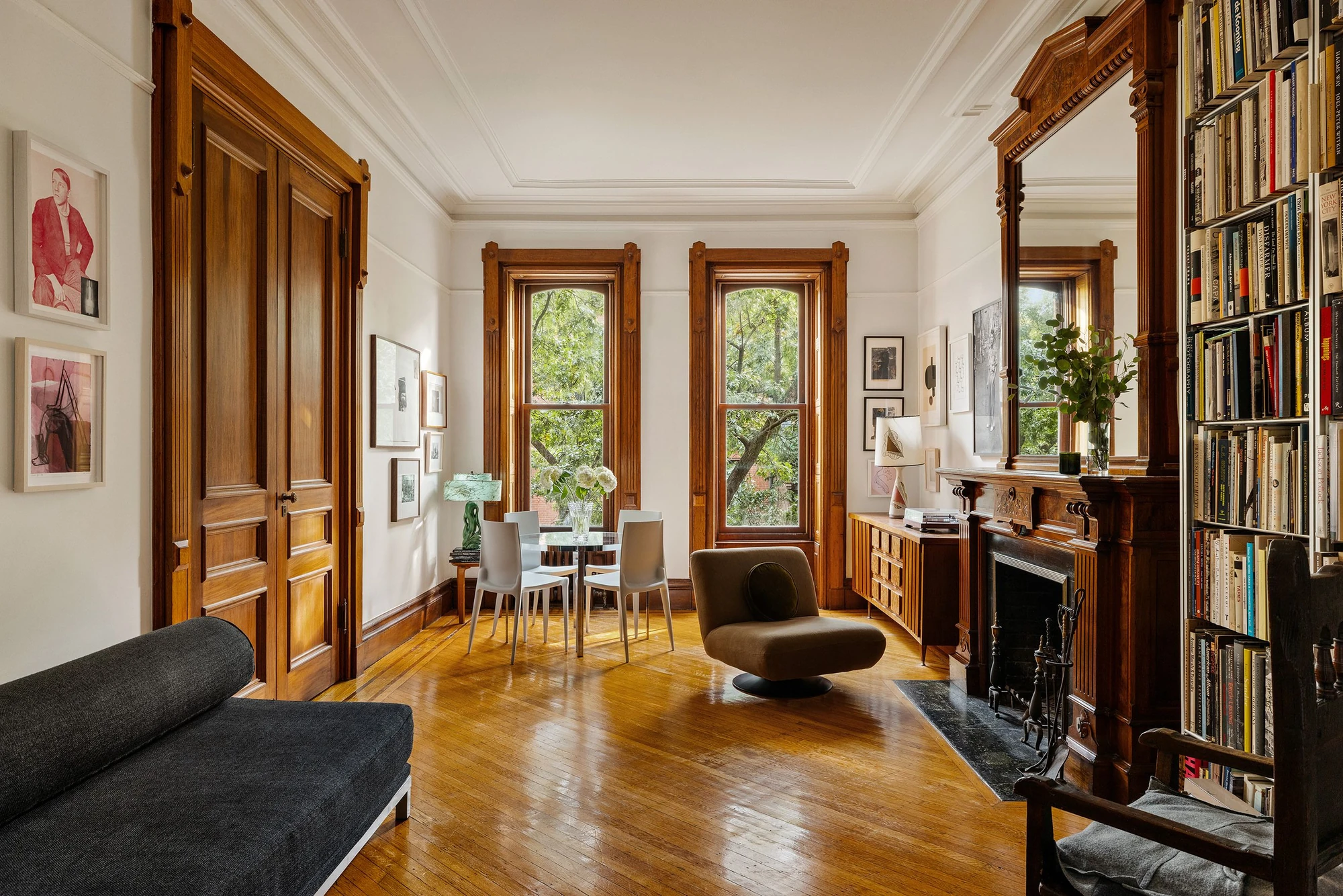 Living and dining room with warm wood trim, a bookcase and tall windows at 39 Remsen Street #4A