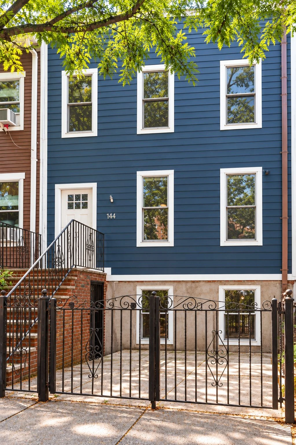Blue-painted Gowanus house with white window trim and a front stoop at 144 11th Street