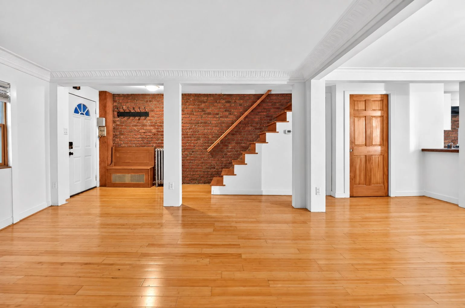 Vacant living space with wood floors and an exposed-brick staircase wall at 144 11th Street