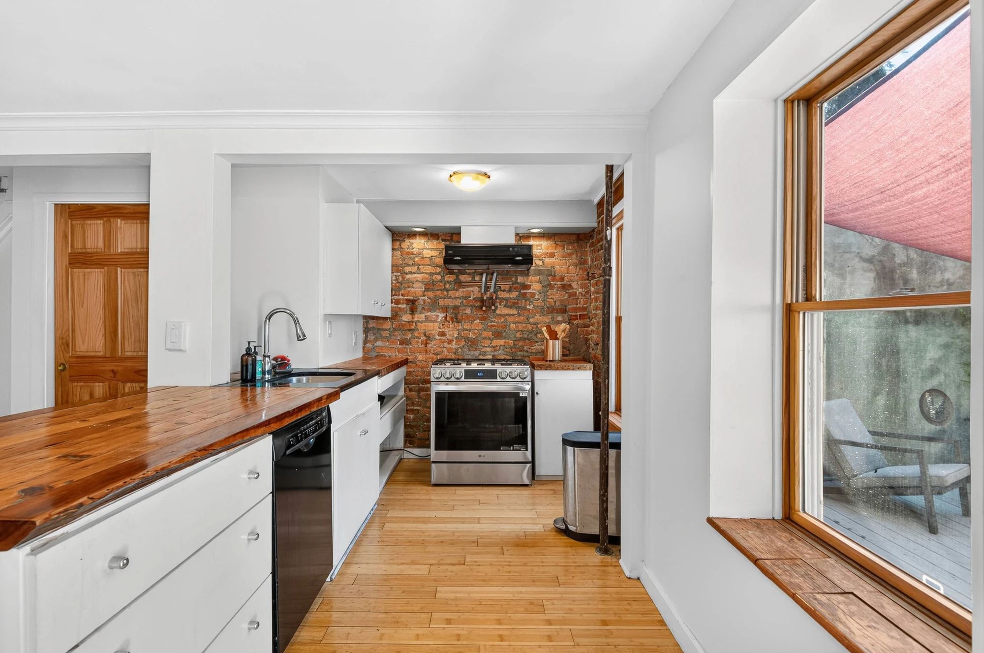 Kitchen with white lower cabinets, wood counters and an exposed-brick wall at 144 11th Street