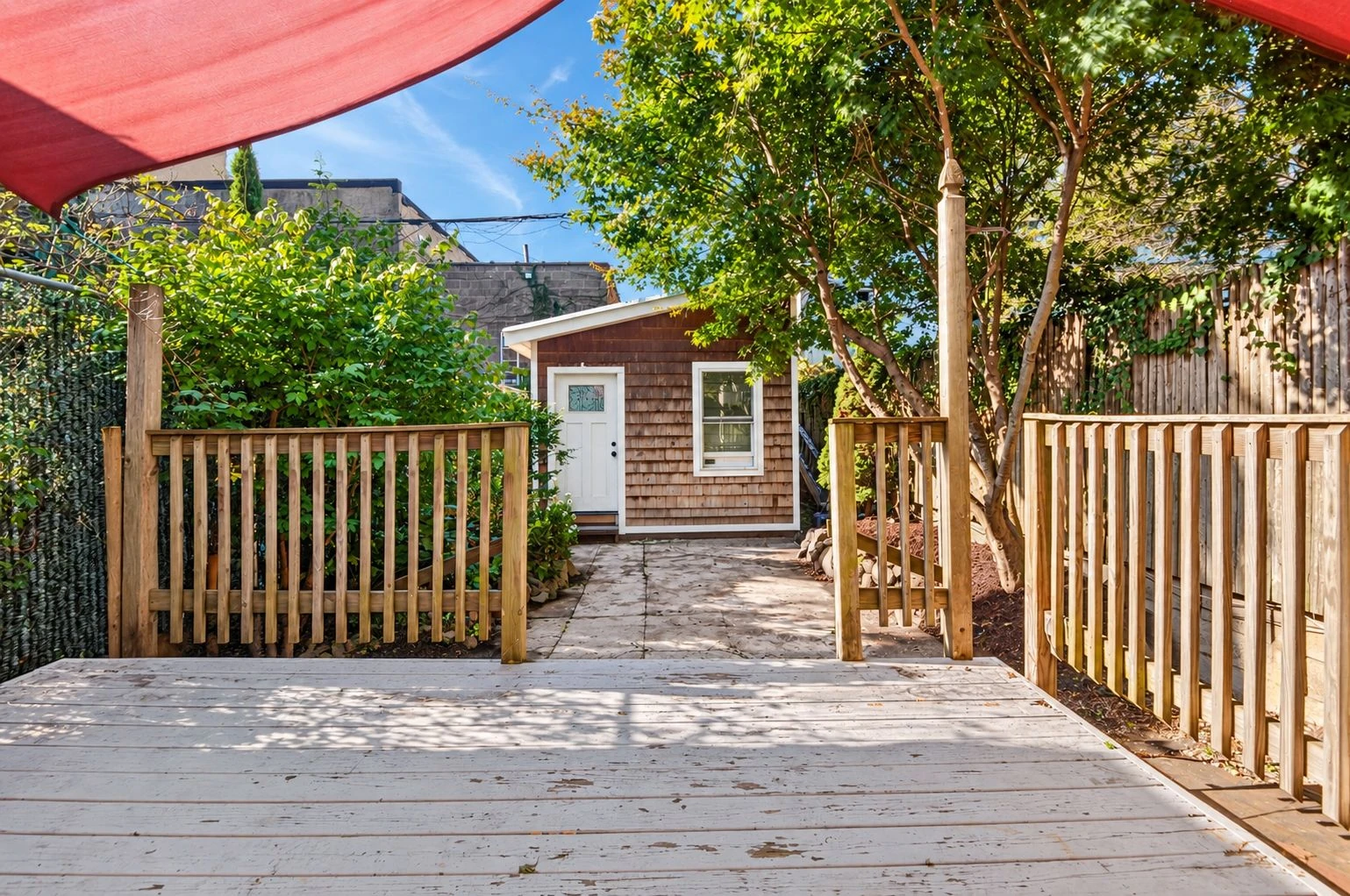 Rear wood deck looking through a planted garden toward a detached studio at 144 11th Street
