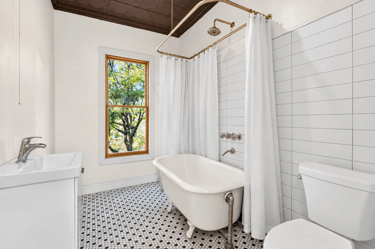 Bathroom with a freestanding tub, mosaic floor and exposed-brick wall at 144 11th Street
