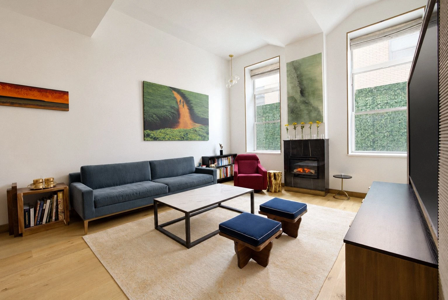 Living room with tall windows, a sofa and an electric fireplace at 257 West 117th Street #1E