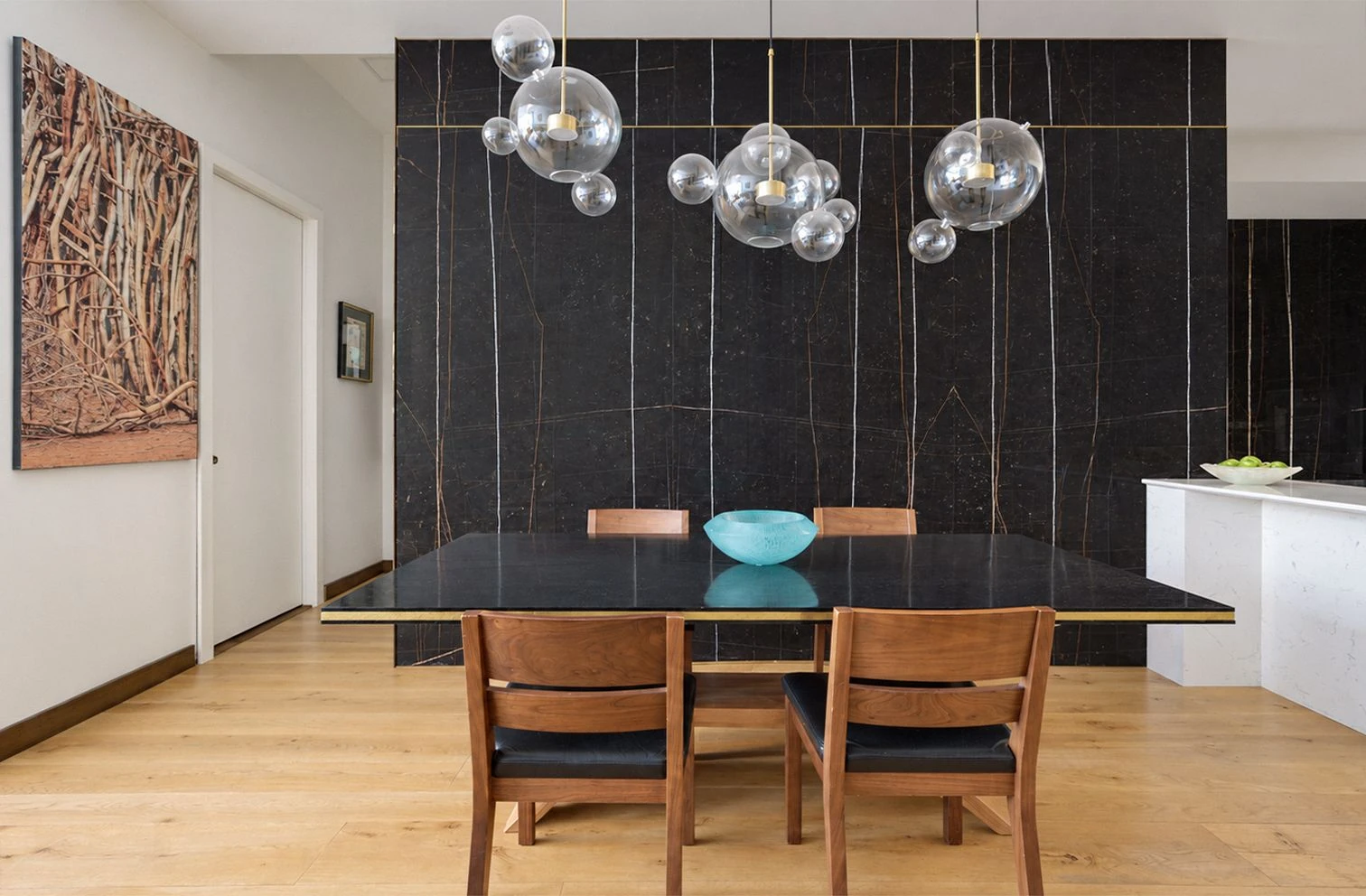 Dining table and glass pendant lights against a dark marble wall at 257 West 117th Street #1E