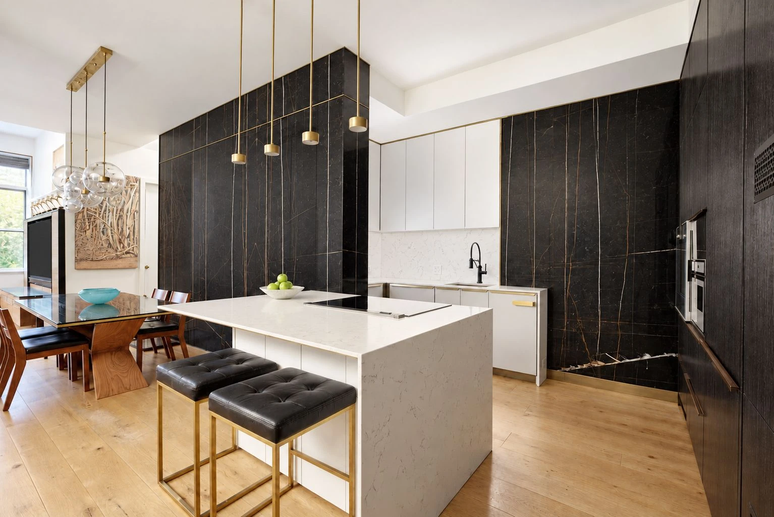 White kitchen counter, dark cabinetry and marble wall beside the dining area at 257 West 117th Street #1E