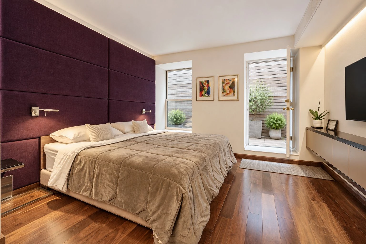 Bedroom with a dark upholstered wall, pale bedding and tall windows at 257 West 117th Street #1E